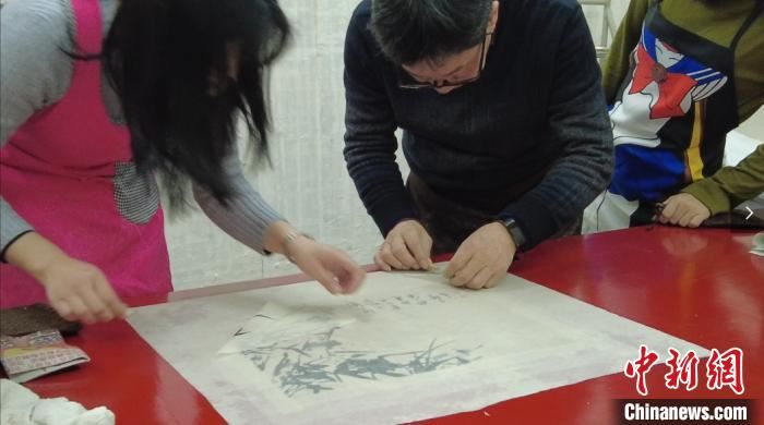 吴福明和他的徒弟正在修复一幅书画。　李韵涵 摄